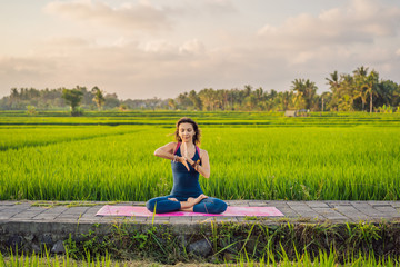 Young woman practice yoga outdoor in rice fields in the morning during wellness retreat in Bali