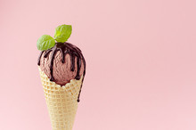 Brown Ice Cream In Waffle Cone With Chocolate Sauce, Mint Leaf On Pastel Pink Background, Closeup, Details, Top, Half.