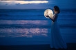 © Anton - Tender image of a girl. Female magic. Beautiful attractive girl in full growth on a night beach with sand hugs the moon, art photo. On a dark background with space. Riddle, astrology, zodiac. Banner.