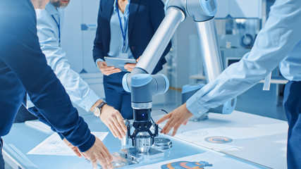 Aufkleber - Team of Industrial Robotics Engineers Gathered Around Table With Robot Arm, They Use Tablet Computer to Manipulate and Program it to Pick Up and Move Metal Component. Focus on Hands