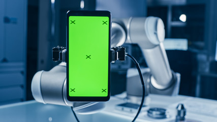 Aufkleber - Real Robot Arm Holding Green Mock-Up Screen Smartphone Device. Industrial Robotic Manipulator End Effector Holds Mobile Phone with Chroma Key Display. Modern Manufacturing Facility / Laboratory 