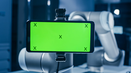 Aufkleber - Robot Arm Holding Green Mock-up Screen Smartphone in Landscape Mode. Industrial Robotic Manipulator End Effector Holds Mobile Phone with Chroma Key Display. 