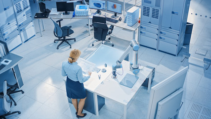 Aufkleber - Stylish Female Industrial Robotics Engineer Looks at Blueprints Engineering Ways to Program and Manipulate Robot Arm for Lifting, Moving Objects. Technology Research Facility for Machine Learning