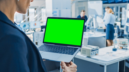 Aufkleber - Engineer Holds Green Mock-up Screen Laptop Computer. In the Background Team of Industrial Engineers Working with Functional Robot Arm in Modern Bright Research Facility