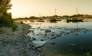 Sticker - wooden riverboats ona calm Loire River at sunset in the French countryside near Orleans