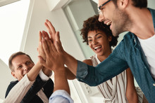 Celebrating Success. Business People Giving Each Other High-five And Smiling While Working Together In The Modern Office