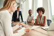 © Friends Stock - Business meeting. Group of young business people looking at documents and discussing something while sitting at the office table