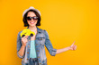Photo of charming toothy beautiful interesting girl wearing cap jeans denim jacket adverting you some taxi while isolated with yellow background