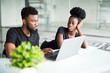© F8  \ Suport Ukraine - Two young african coworkers working together in a modern office. African black business partners using laptop and discussing new startup project.
