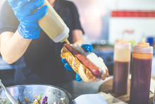 Man Holding Hot Dog And Adding Mustard. Street Fast Food Vendor Concept.