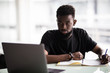 © F8  \ Suport Ukraine - Young African man looking at camera with laptop in modern office