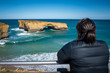 Tourist staring out to sea looking at London Bridge landmark on Great Ocean Road in Victoria Australia