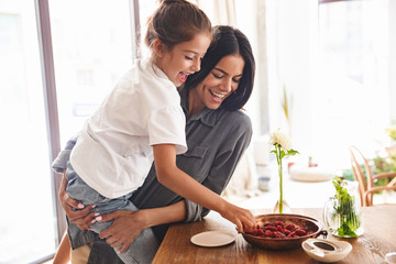 Wall Mural - image of amazing family mother smiling and holding her little daughter in hands at cozy apartment