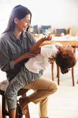 Wall Mural - image of attractive family woman smiling and having fun with her little daughter at cozy apartment