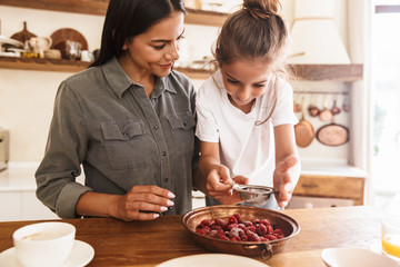 Wall Mural - image of attractive family woman and her little daughter cooking together meal with raspberry at coz