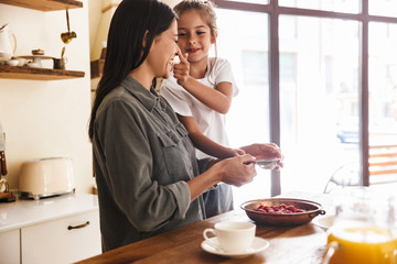 Wall Mural - image of attractive family woman and her little daughter cooking together meal with raspberry at coz