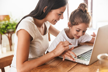 Wall Mural - image of beautiful family woman and her little daughter smiling and using laptop computer together i