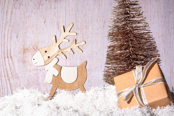 New Year and Christmas background for greetings, banner, postcard, advertisement with place for text. Wooden deer on a sled and a box with a gift close-up on a background of a golden Christmas tree. C