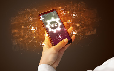 Sticker - Female hand holding smartphone with NFC abbreviation, modern technology concept