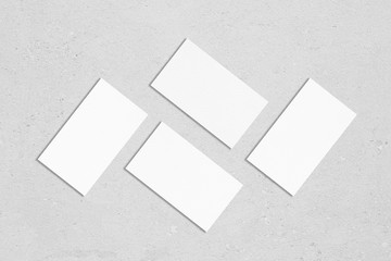 Poster - Four white rectangle business card mockups with soft shadows lying on grey concrete background. Flat lay, top view