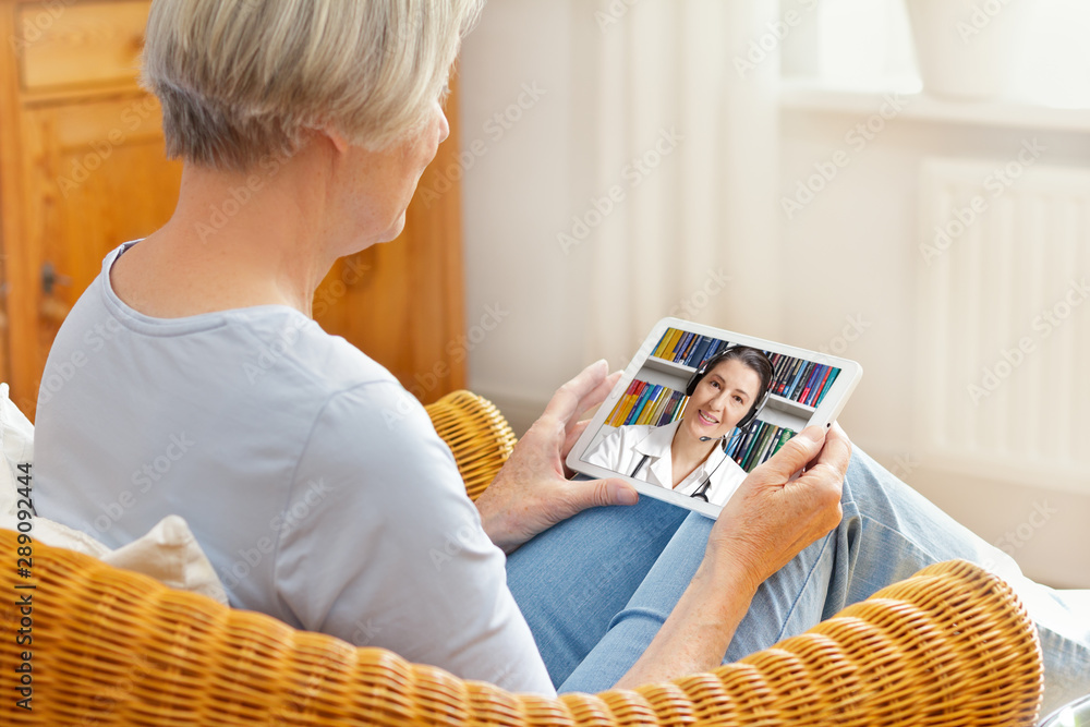 telemedicine concept, old woman with tablet pc during an online consultation with her doctor in her living room - obrazy, fototapety, plakaty 
