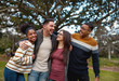 © StratfordProductions - Diverse group of happy young american friends standing together in front of tree at park - young and fun and outdoors