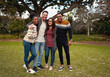 © StratfordProductions - Smiling group of friends in fashionable casual clothing standing together in park outdoors smiling and very happy - looking at camera