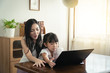 © KOTL - Beautiful asian mother and daughter working together at home office by the window. in concept of single mom or single parent.