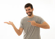 © SB Arts Media - Charming smiling young man pointing finger at empty copy space for advertisement