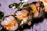 Fototapeta Maki - Sushi Roll viewed from above. On black stone.