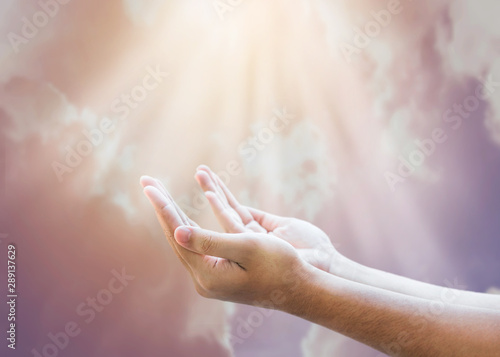 Fotografía Open empty human hands raise up to the sun light that come down through bold cl