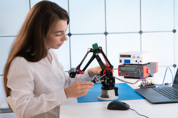 Wall Mural - A young woman writes an algorithm for the robot arm. Science Research Laboratory for Robotic Arm Model. Computer Laboratory