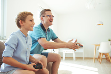 Wall Mural - Happy young father and  his son playing computer games  with controllers very emotional