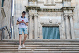 Fototapeta Na drzwi - young teenage man with mobile phone walking in the city