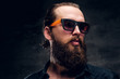 © Fxquadro - Handsome bearded man in sunglasses is posing for photographer at dark photo studio.
