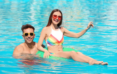 Wall Mural - Happy young couple with inflatable ring in swimming pool