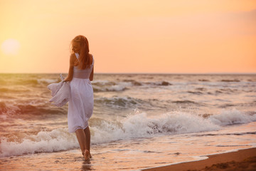 Poster - Beautiful young woman on beach at sunset