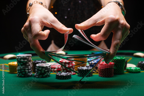 Fotomural Girl dealer or croupier shuffles poker cards in a casino on the background of a table, chips,