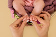 mother and baby. Feet of the newborn baby girl with pink flowers, fingers on the foot, maternal care, tenderness. 