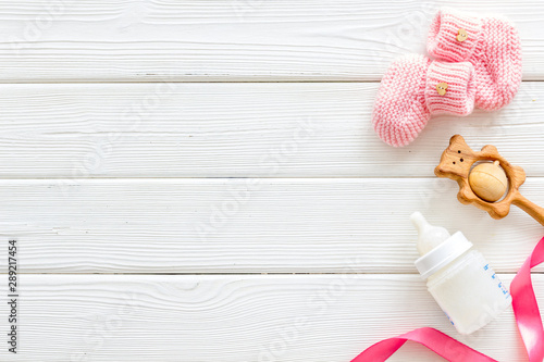 Fotografía Booties for newborn girl with rattle and bottle on white wooden background top v