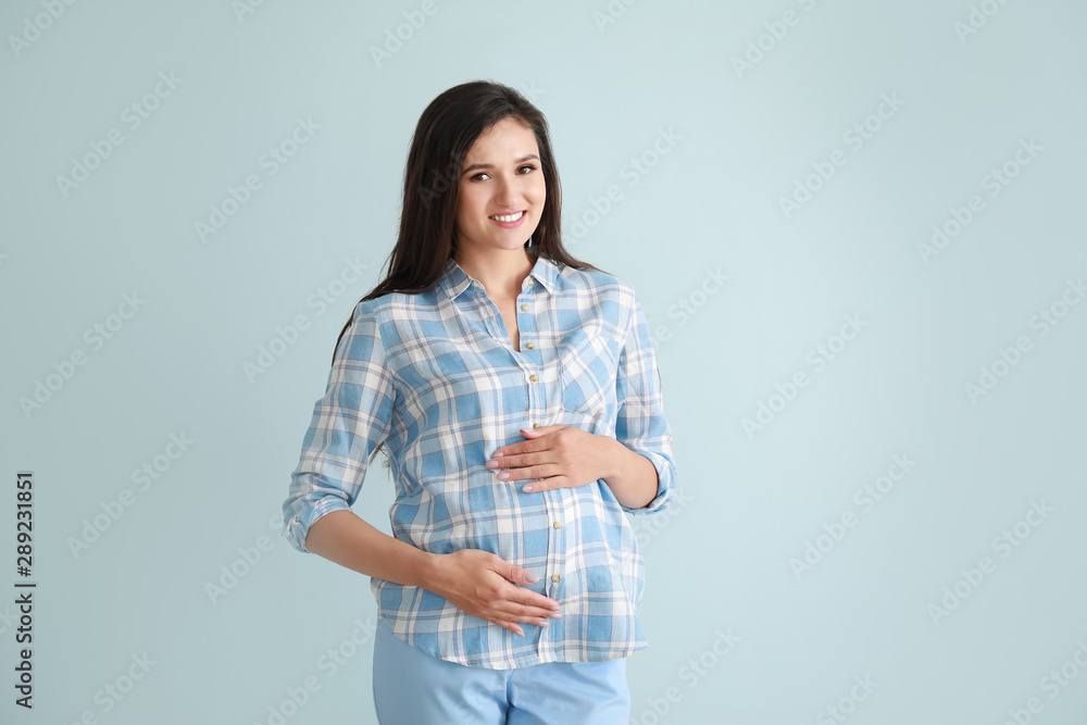 Young pregnant woman on color background