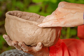 Making clay dishes manually. Big hands. On the street