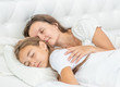 © Ermolaev Alexandr - Mother and daughter sleep together on the bed at home
