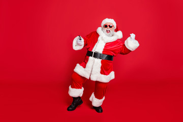 Poster - Forever young. Full length photo of excited santa in hat using cell phone device raising fists screaming yes have party wearing belt eyeglasses eyewear isolated over red background