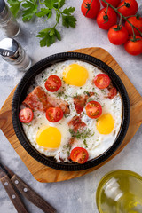 Wall Mural - Fried eggs, bacon and vegetables on a frying pan. Breakfast time. Top view.