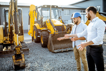 builder choosing heavy machinery for construction with a sales consultant on the open ground of a sh