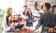 Young friends having fun drinking beer on balcony at house dinner party - Happy people eating pizza at fancy alternative restaurant together - Dining lifestyle concept on bright sunshine filter