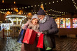 © Syda Productions - sale, winter holidays and people concept - happy senior couple with shopping bags at christmas market souvenir shop on town hall square in tallinn, estonia