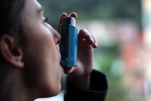 Health And Medicine - Young Girl Using Blue Asthma Inhaler To Prevent An Asthma Attack.