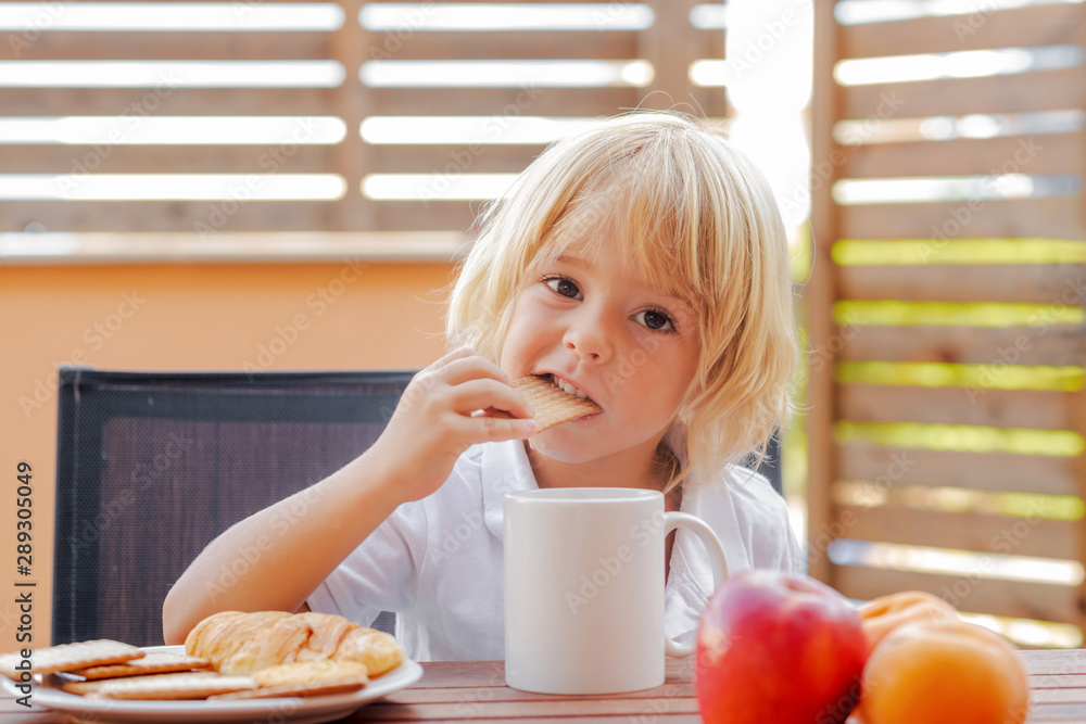 Child bites cookie at snack or breakfast - obrazy, fototapety, plakaty 
